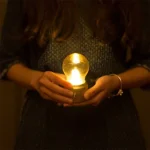 Bougie décorative en forme d’ampoule tenue dans la main
