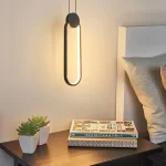 Lampe murale LED ovale au‑dessus d’une table de nuit avec plantes.