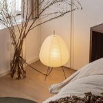 Lampe japonaise en papier diffusant une lumière chaude près d’un vase.