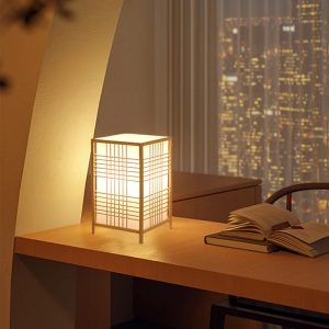 Lampe japonaise en bois éclairant un bureau de nuit.