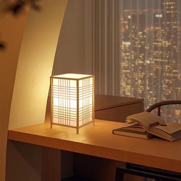 Lampe japonaise en bois éclairant un bureau de nuit.