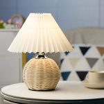 Lampe de chevet en rotin avec abat‑jour plissé sur table d’appoint.