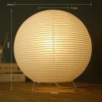 Lampe sphérique en papier diffusant une lumière chaude sur une table en bois.