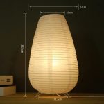 Lampe ovale en papier allumée sur un meuble